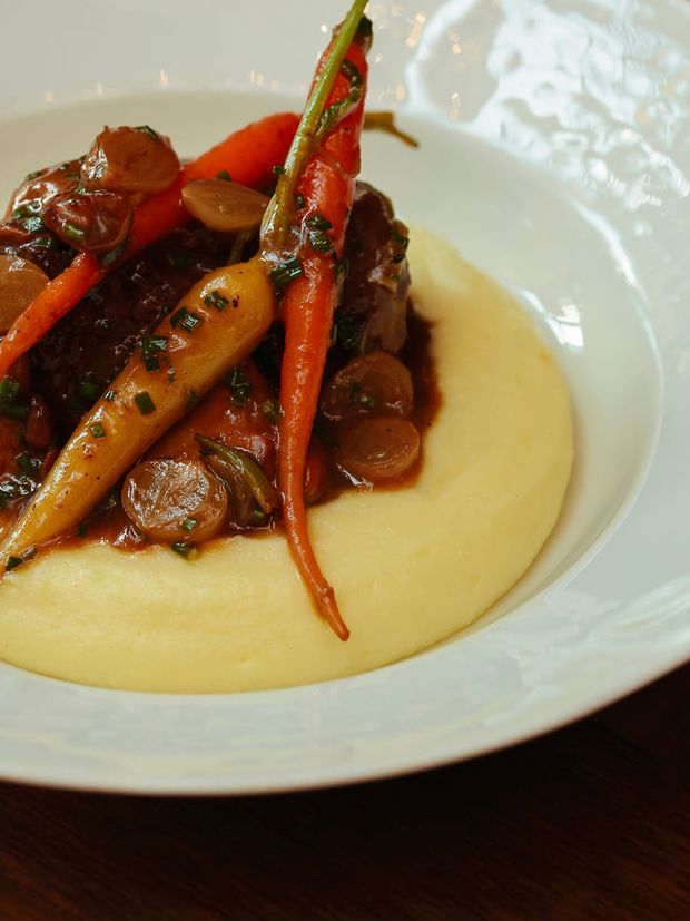 A plated main course at Bisou — glazed carrots on purée, on a white plate.
