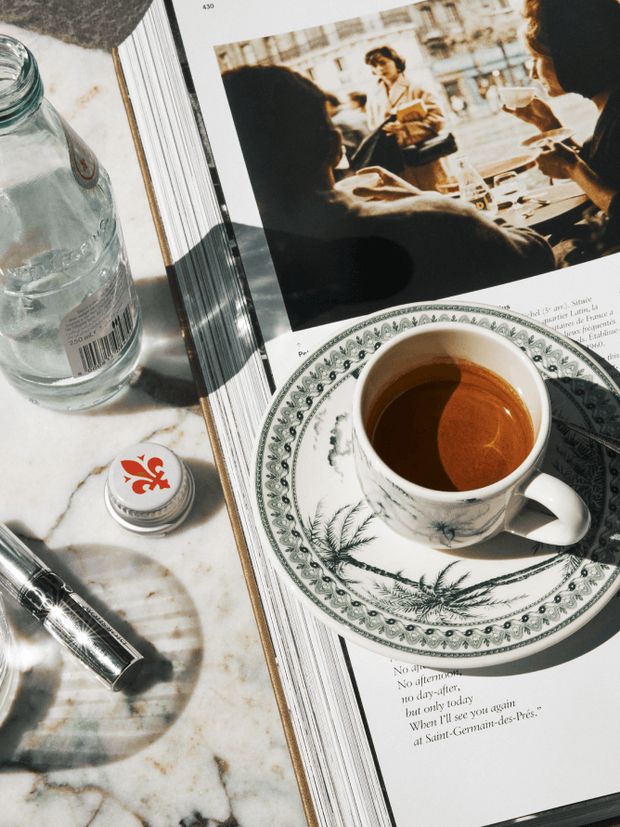 An espresso in a patterned cup beside a magazine on a marble table at Bisou.